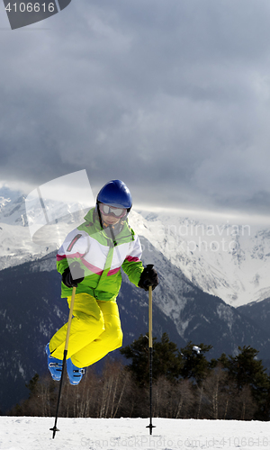 Image of Young skier jump with ski poles in sun winter mountains
