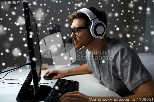 Image of man in headset playing computer video game at home