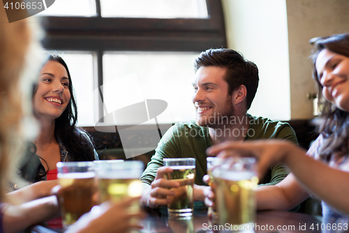 Image of happy friends drinking beer at bar or pub