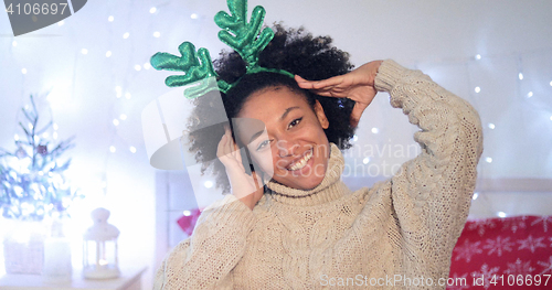 Image of Playful young woman wearing green reindeer antlers