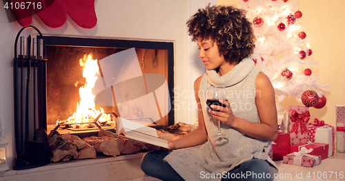 Image of Young woman reading a drinking red wine