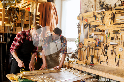 Image of carpenters with ruler and wood plank at workshop