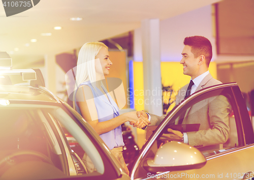 Image of happy woman with car dealer in auto show or salon