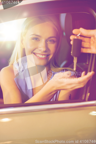 Image of happy woman getting car key in auto show or salon