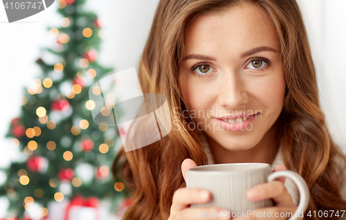 Image of close up of woman with tea cup over christmas tree