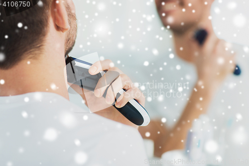 Image of close up of man shaving beard with trimmer