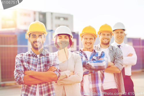 Image of group of smiling builders in hardhats outdoors