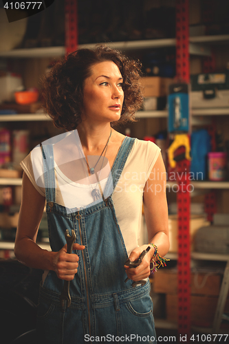 Image of car mechanic woman in blue overalls with a wrench in her hand