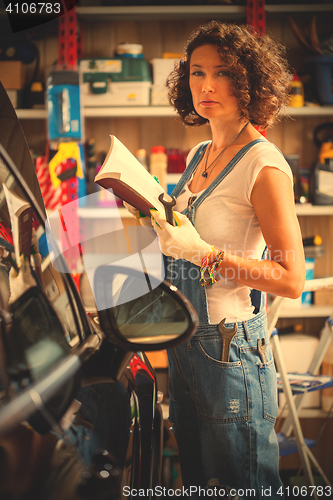 Image of woman mechanic in blue overalls with instructions for repair and