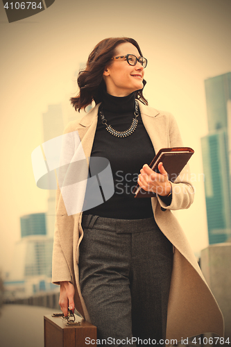 Image of Smiling beautiful middle-aged woman goes in a white coat 