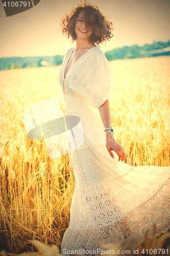 Image of woman in fashionable white dress dancing in a golden field