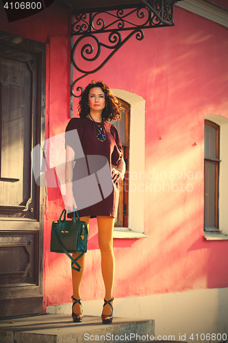 Image of pretty woman in a burgundy dress with a green handbag
