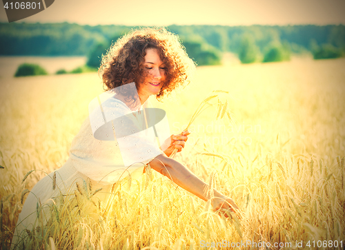 Image of smiling woman in a light dress collects in the ears of the field