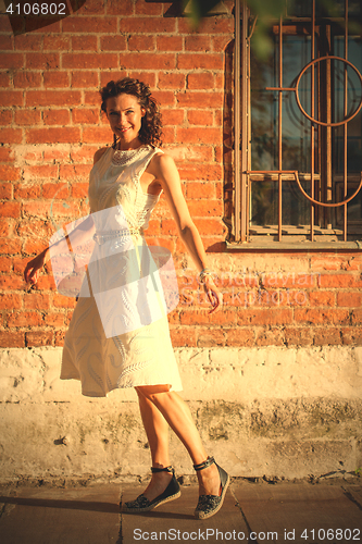 Image of georgeous woman in white dress dancing in the street