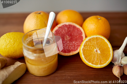 Image of honey, citrus fruits, ginger and garlic on wood