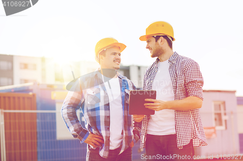 Image of smiling builders in hardhats with tablet pc