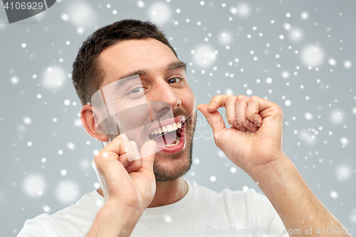 Image of man with dental floss cleaning teeth over snow