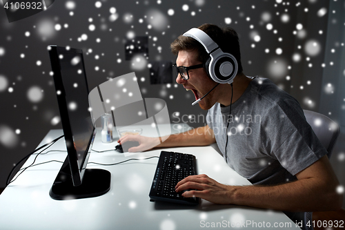 Image of man in headset playing computer video game at home