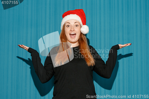 Image of Surprised christmas girl wearing a santa hat