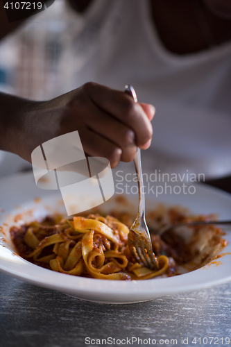 Image of a young African American woman eating pasta