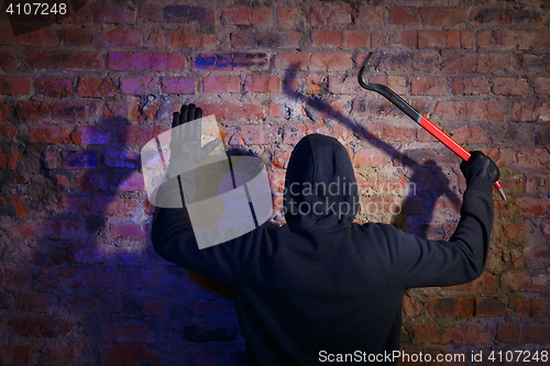 Image of Burglar surrenders against brick wall