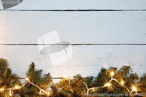 Image of Wooden surface decorated with fir branches and lightbulb. Christmas card