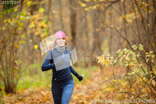 Image of Woman runner in the morning autumn park