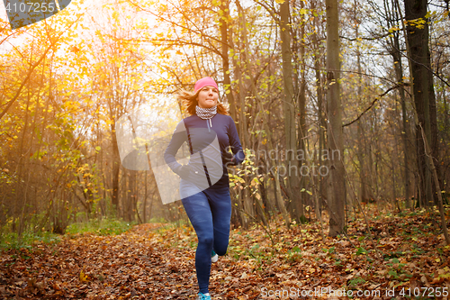 Image of Young sportswoman running at park