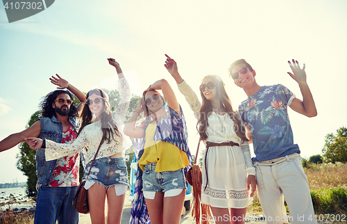 Image of happy young hippie friends dancing outdoors