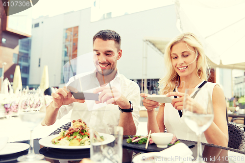 Image of happy couple with smatphone photographing food