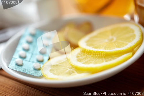 Image of lemon slices, pills and ginger on plate