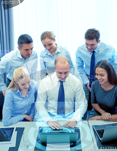 Image of smiling business people with laptop in office