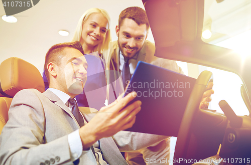 Image of happy couple with car dealer in auto show or salon