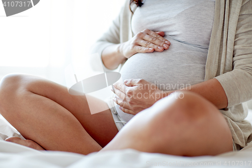 Image of close up of pregnant woman sitting in bed at home