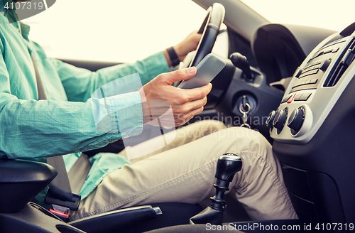 Image of close up of man with smartphone driving car