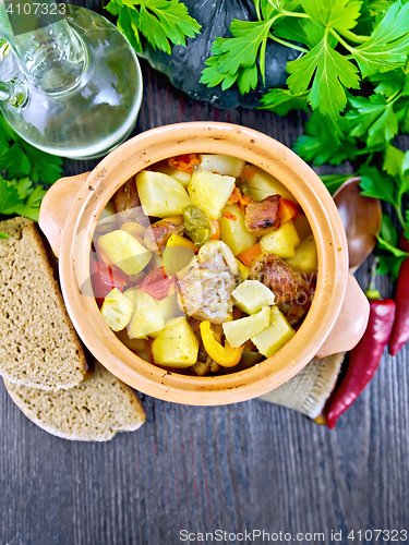 Image of Roast meat and vegetables in clay pot on board top