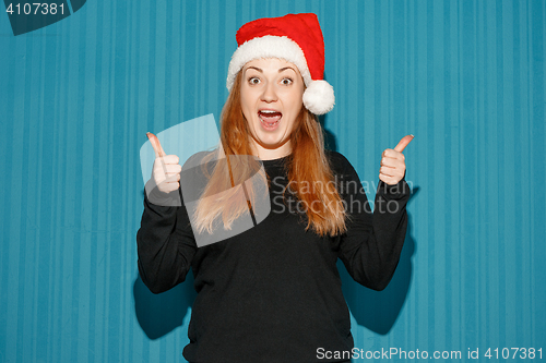 Image of Surprised christmas girl wearing a santa hat