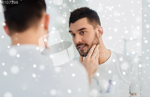 Image of happy young man looking to mirror at home bathroom