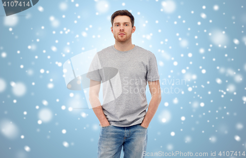 Image of young man in gray t-shirt and jeans over snow