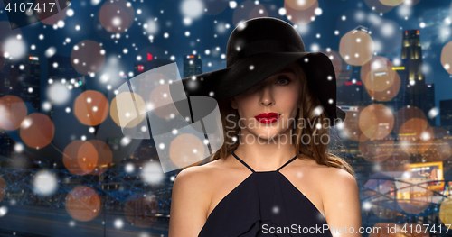 Image of beautiful woman in black hat over night city