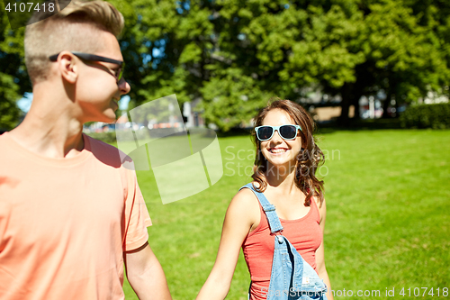 Image of happy teenage couple walking at summer park