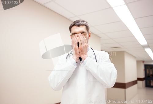 Image of sad or crying male doctor at hospital corridor