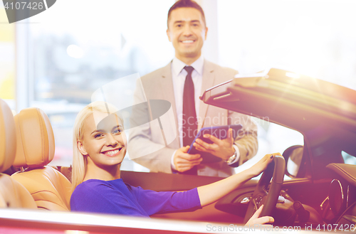 Image of happy woman with car dealer in auto show or salon