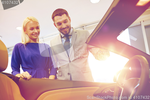 Image of happy couple buying car in auto show or salon