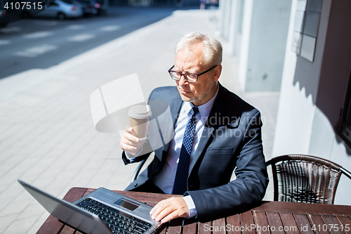 Image of senior businessman with laptop drinking coffee