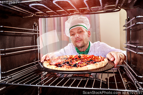 Image of Chef cooking pizza in the oven.