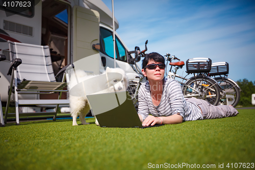 Image of Woman on the grass with a dog looking at a laptop