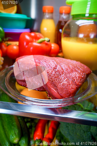 Image of Fresh raw meat on a shelf open refrigerator