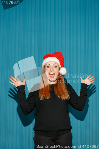 Image of Surprised christmas girl wearing a santa hat