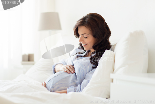 Image of happy pregnant woman lying on bed at home